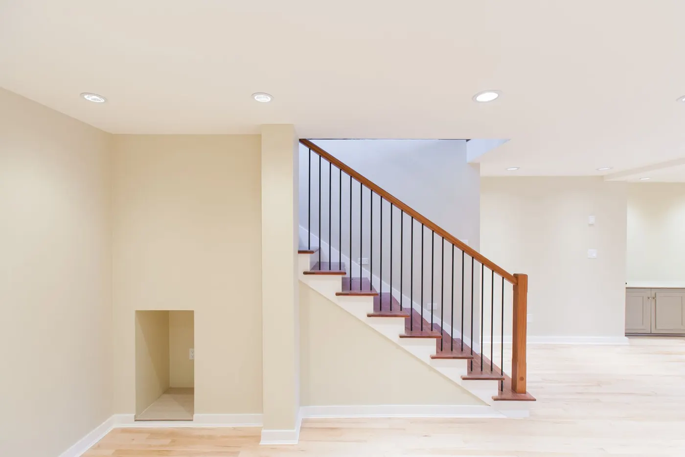 A finished basement with a staircase and white walls