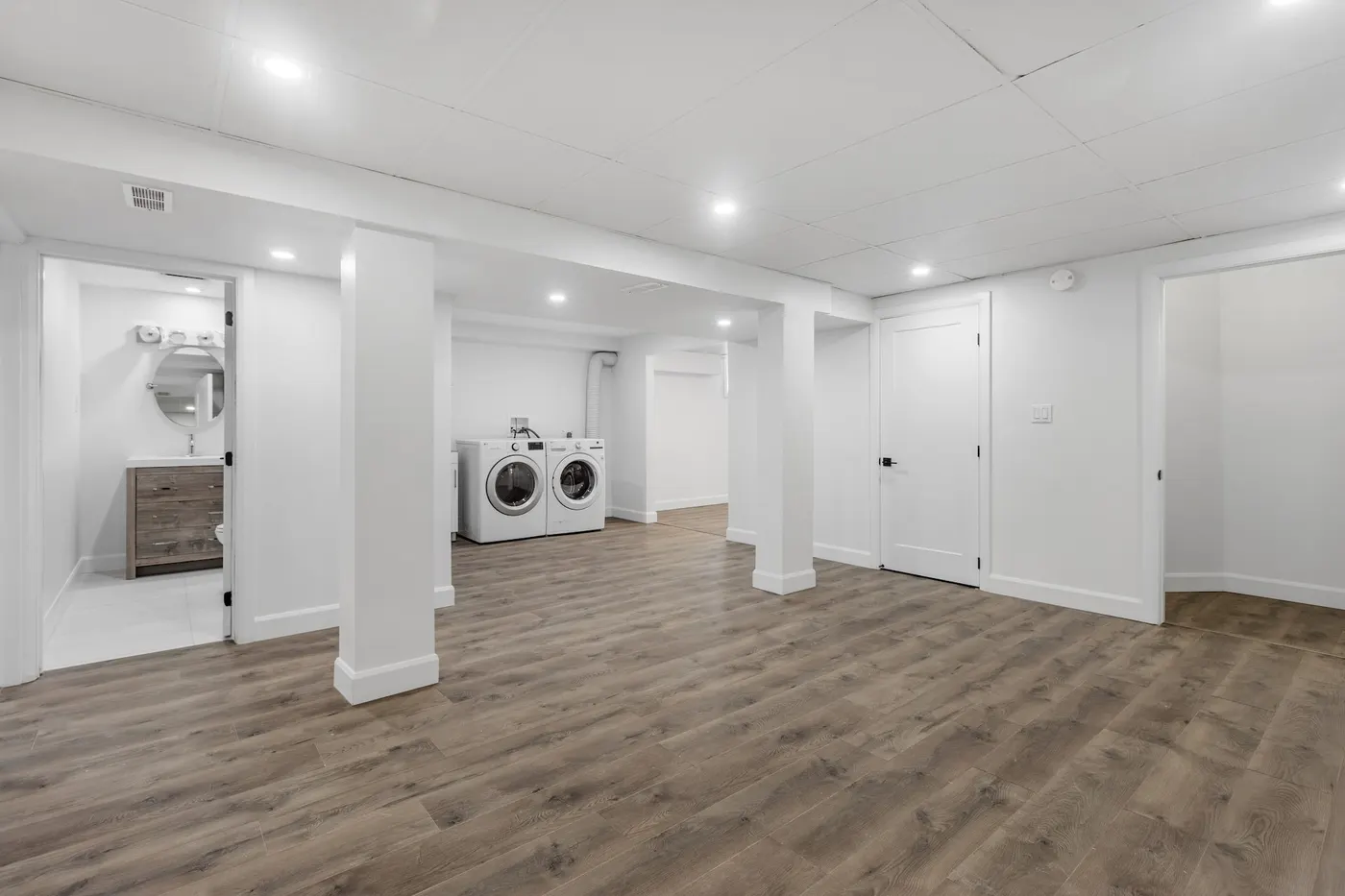 A finished basement with plank flooring and a laundry area