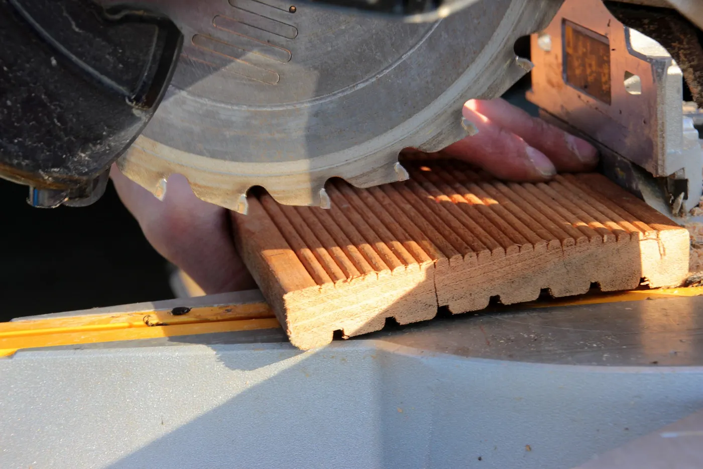 A miter saw cutting a length of wood trim