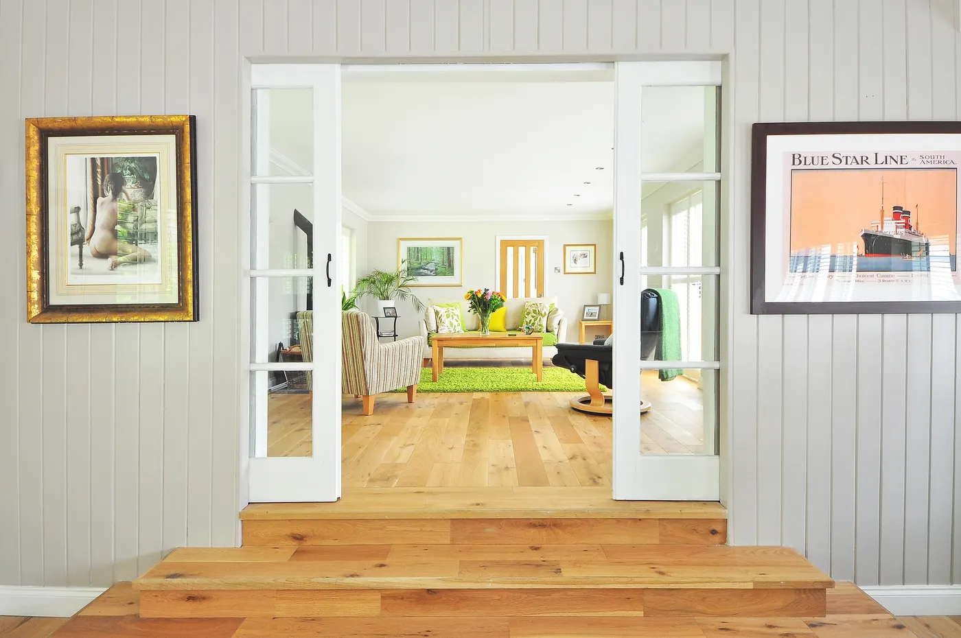 A hallway opening onto a living room with crown molding at the ceiling