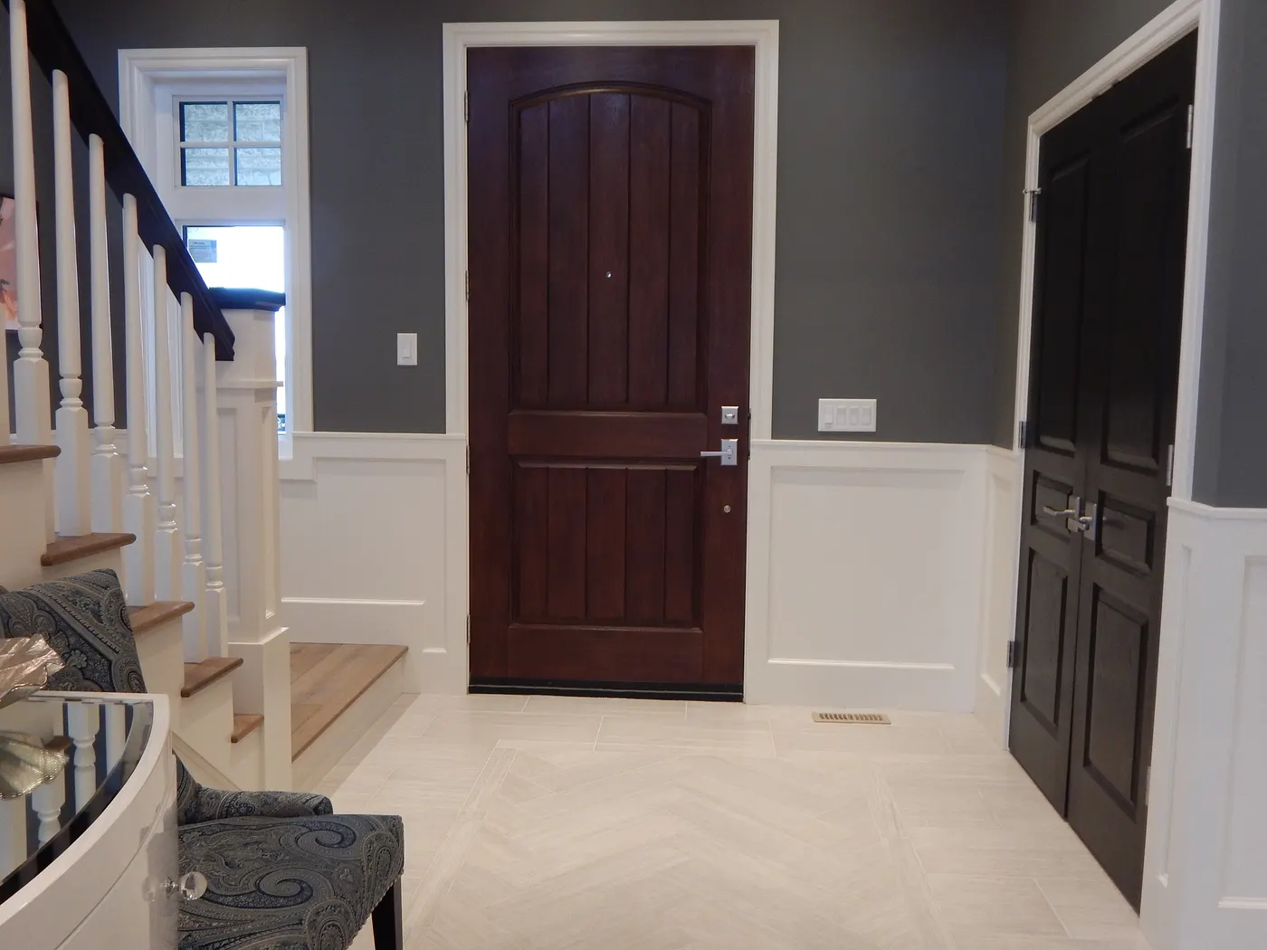 A foyer with wainscoting, door casings and painted stair balusters