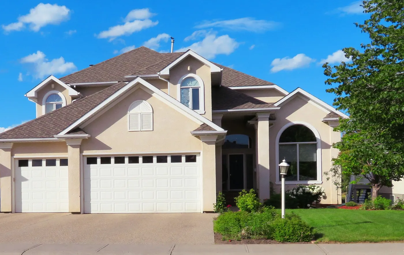 A two-story house with a shingle roof and a three-car garage