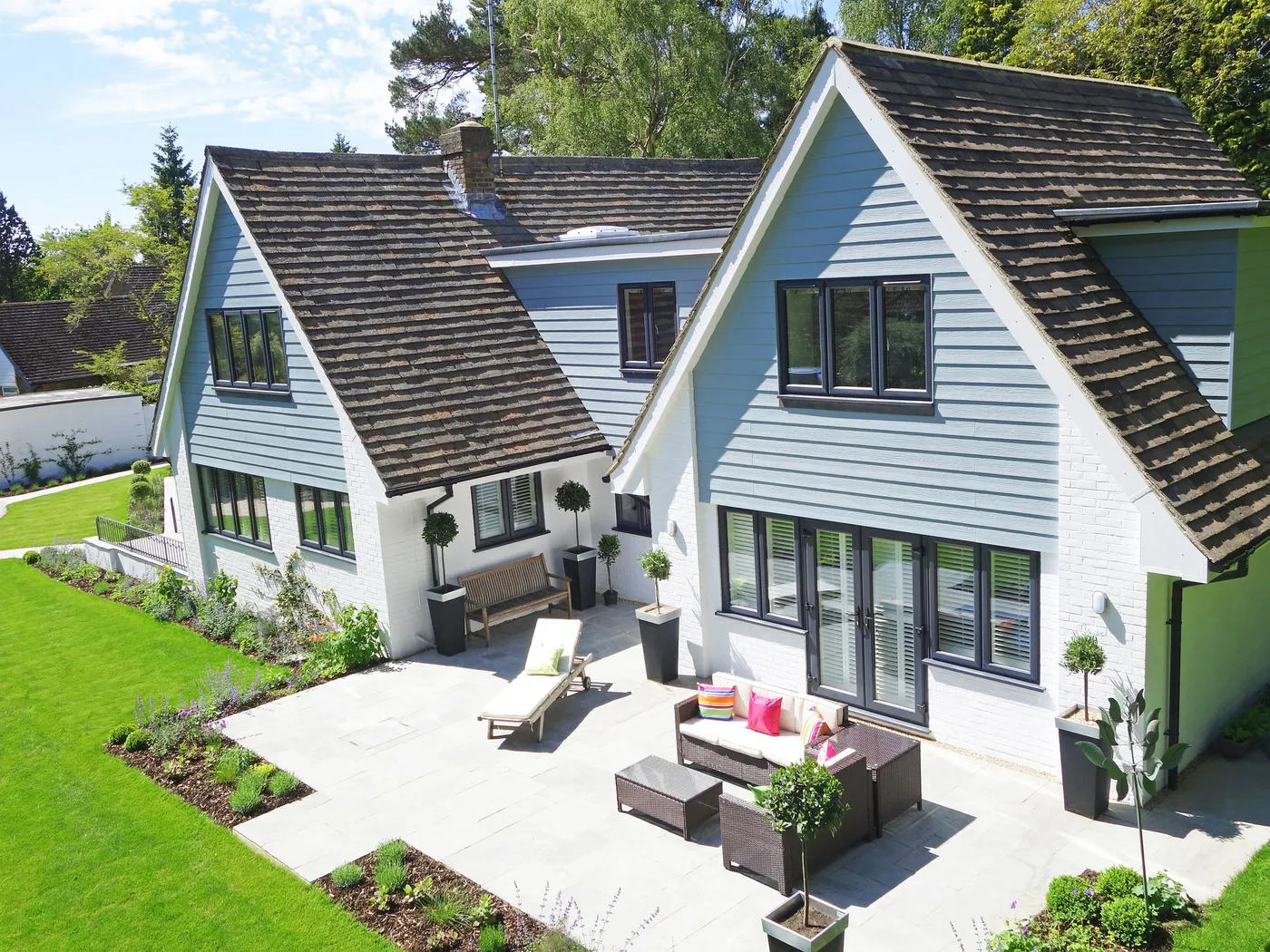 A gabled house with blue lap siding, new windows and a patio
