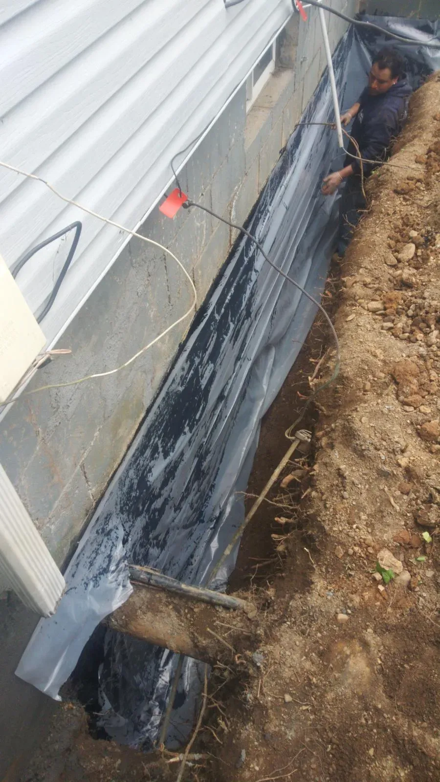 Waterproofing membrane on an excavated foundation wall beside a house