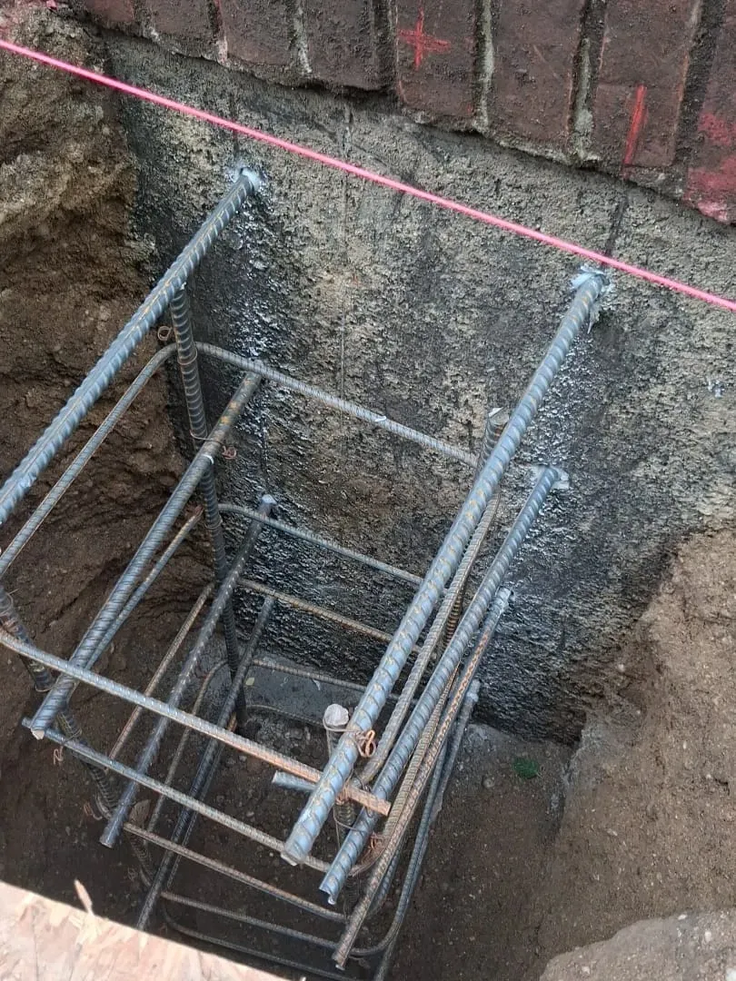 A rebar cage set against a coated foundation wall