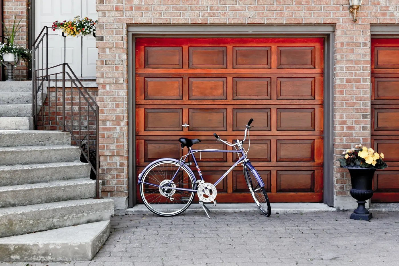 A wooden carriage-style garage door on a brick home