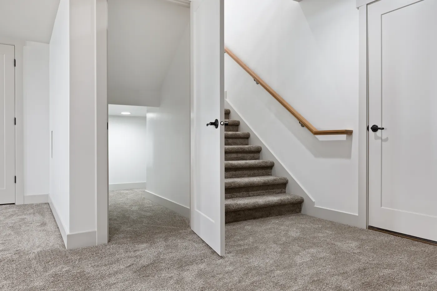 A finished hallway with new carpet, white doors and trim