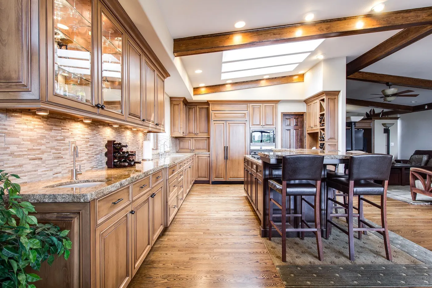 A kitchen with wood cabinets, granite countertops and an island with stools