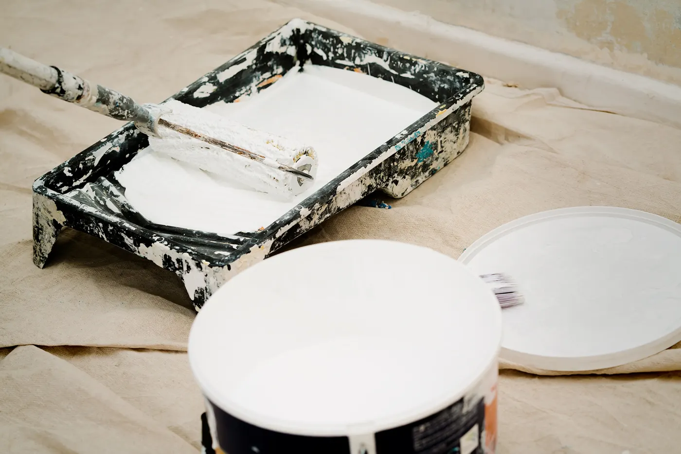 A paint roller and tray ready on a drop cloth