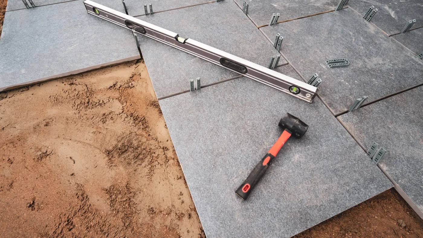 Large-format tiles being laid with spacers, a level and a mallet