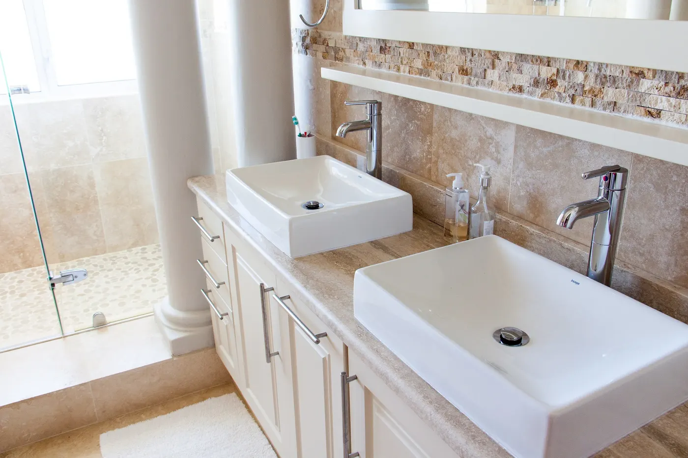 A bathroom with tiled walls, a mosaic border and a tiled shower